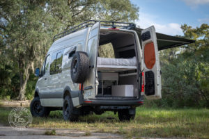 camper van with back doors open and bed inside